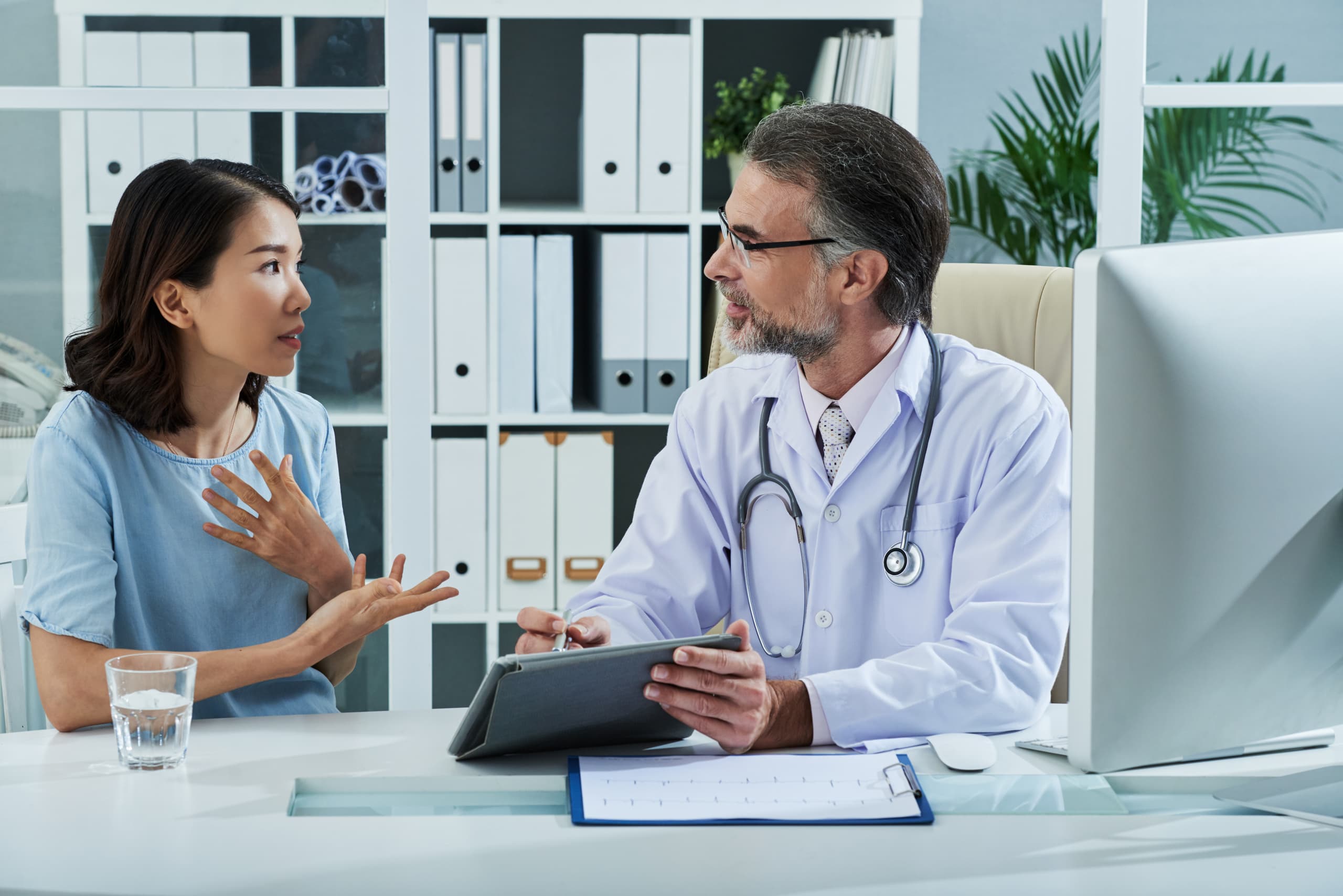 Doctor consulting with a patient while using ambient AI support in a modern clinic room